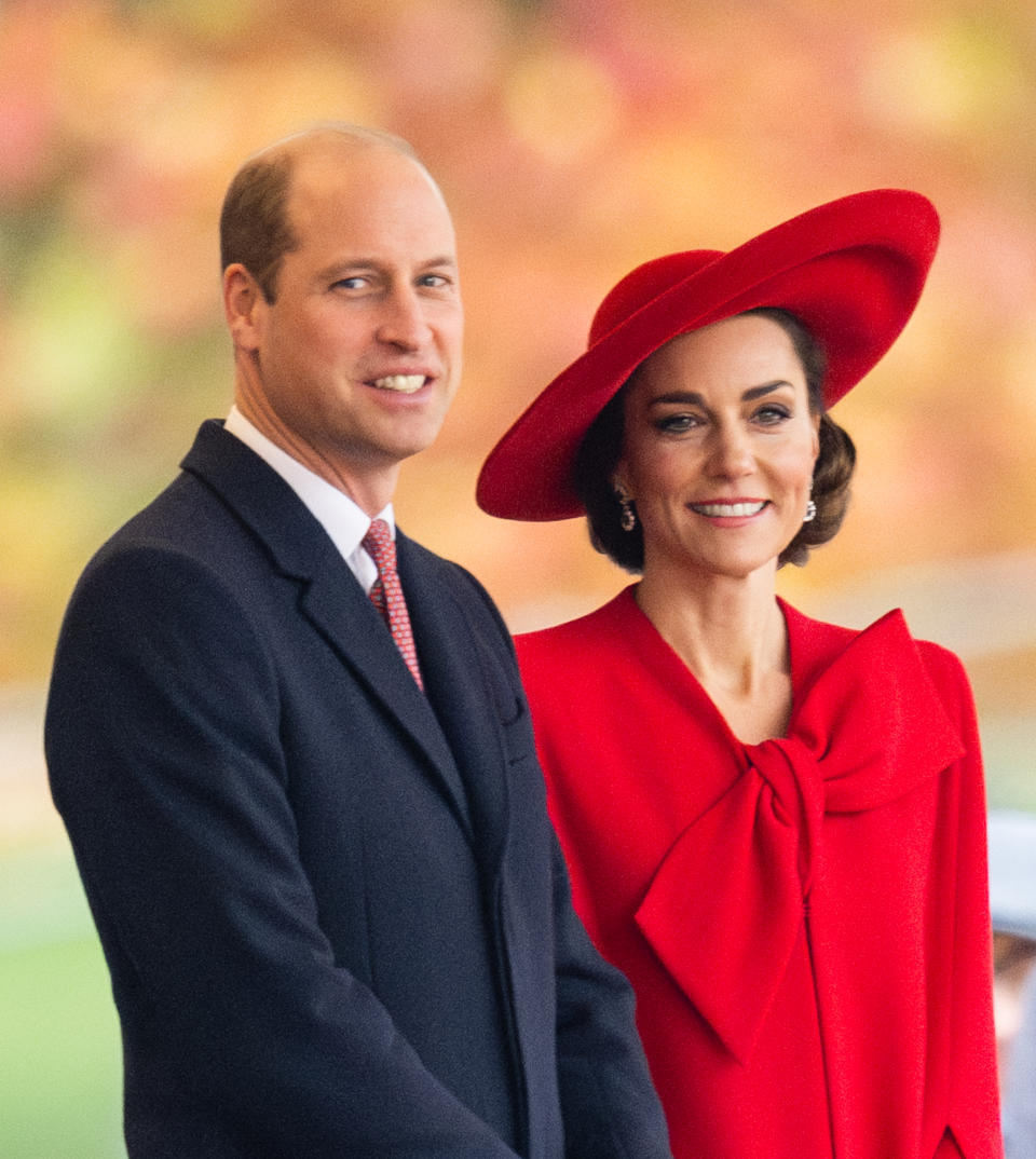 Prince William and Kate Middleton pose together; Kate wears a stylish hat and an elegant outfit with a large bow