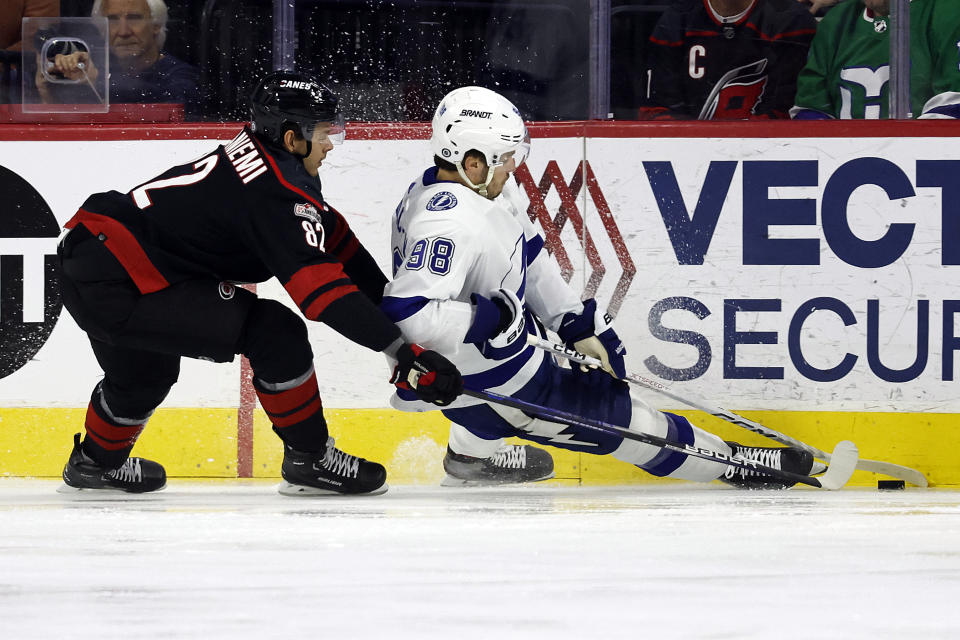 Tampa Bay Lightning's Mikhail Sergachev (98) loses an edge as he battles for the puck with Carolina Hurricanes' Jesperi Kotkaniemi (82) during the first period of an NHL hockey game in Raleigh, N.C., Sunday, March 5, 2023. (AP Photo/Karl B DeBlaker)