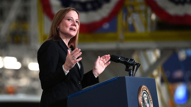Mary Barra speaking at a podium with the US presidential seal