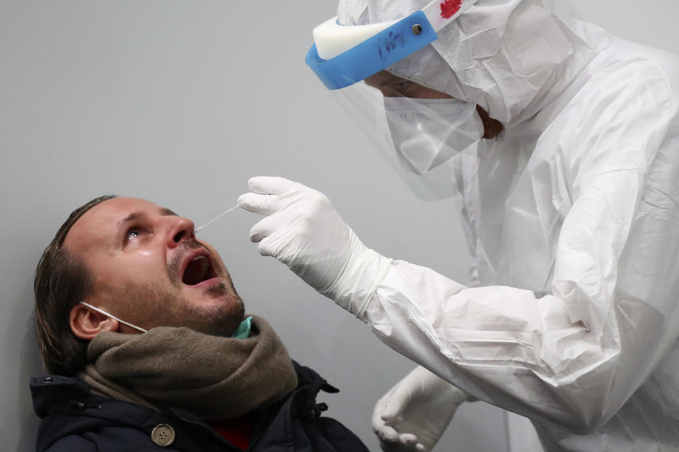 An employee of a new Lufthansa corona quick test center takes a test of a passenger at the airport in Munich, Germany, Thursday, Nov. 12, 2020. Lufthansa starts the first test runs for comprehensive Covid-19 antigen rapid tests on selected routes between Munich and Hamburg. (AP Photo/Matthias Schrader)