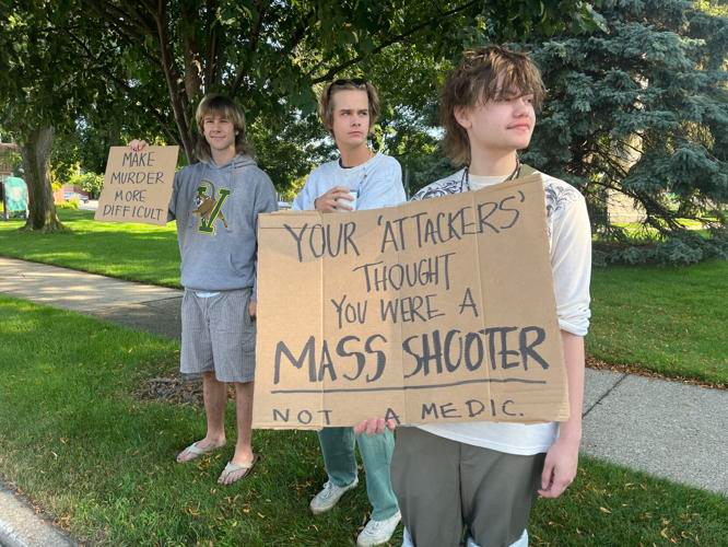 Finch Arnold, front right, holds a sign in front of his two friends at a protest Wednesday, July 19.