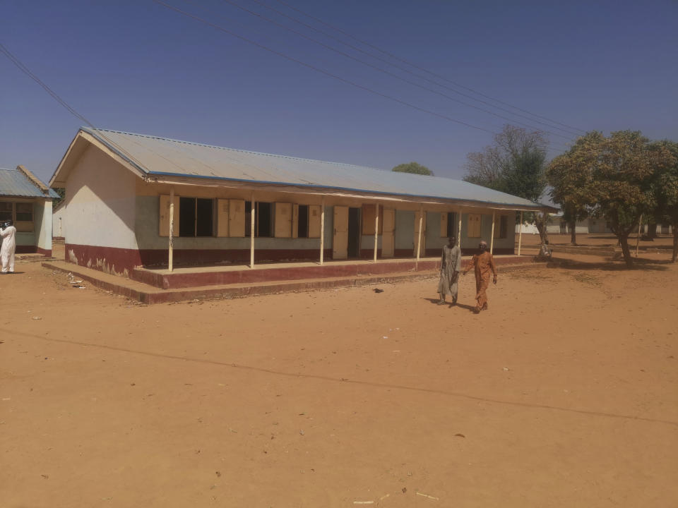 Two people walk pass Kankara's Government Science Secondary School.