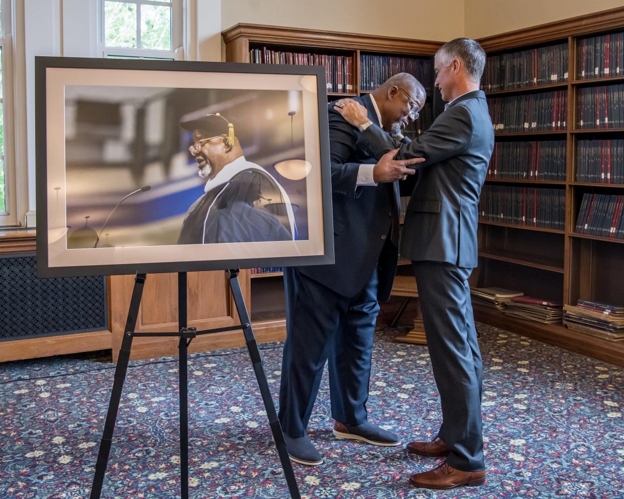 Drake University President Marty Martin embraces Wayne Ford, former state legislator and founder of the social services nonprofit Urban Dreams, on May 19, 2022, at the unveiling of Ford's official portrait at Drake's Cowles Library.