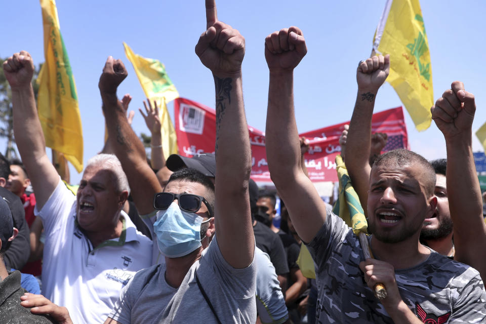 Hezbollah supporters chant slogans as they hold their group's flags while protesting the visit to Lebanon by Gen. Frank McKenzie, the head of U.S. Central Command, outside ​​the Rafik Hariri International Airport in Beirut, Lebanon, Wednesday, July 8, 2020. (AP Photo/Bilal Hussein)