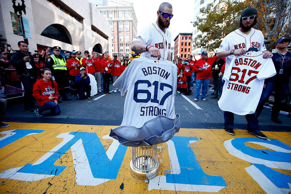 People holding "Boston 617 Strong" T-shirts at the finish line with a crowd behind them