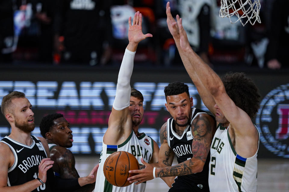 Brooklyn Nets guard Chris Chiozza (4) cuts between Milwaukee Bucks guard Kyle Korver (26) and center Robin Lopez (42) during the first half of an NBA basketball game Tuesday, Aug. 4, 2020 in Lake Buena Vista, Fla. (AP Photo/Ashley Landis)