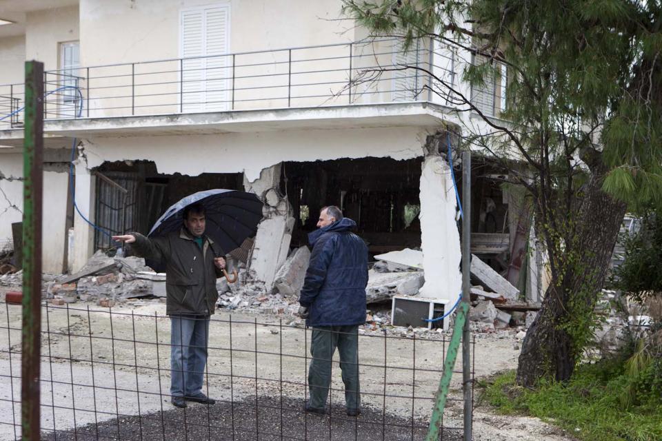 Residents look at a damaged building after an earthquake in Lixouri on the island of Kefalonia, western Greece on Monday, Feb. 3, 2014. A strong earthquake with a preliminary magnitude between 5.7 and 6.1 hit the western Greek island of Kefalonia before dawn Monday, sending scared residents into the streets just over a week after a similar quake damaged hundreds of buildings, reviving memories of a disaster in the 1950s. (AP Photo)