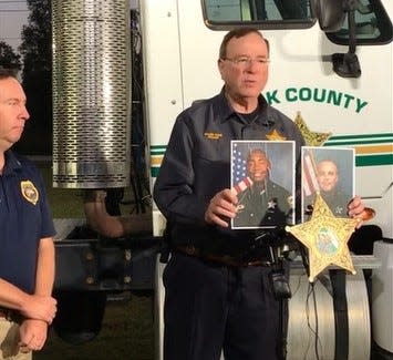 Polk County Sheriff Grady Judd, with State Attorney Brian Haas at left, holds up the photos of two deputies who were shot shortly after midnight Saturday by a "sovereign citizen" suspect at the Hunt Fountain athletic complex in North Lakeland.