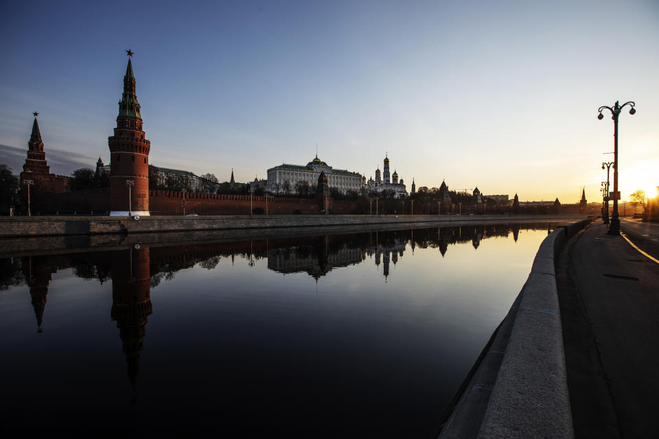 The Kremlin and its towers and churches are reflected in the Moscow River along a deserted embankment as the sun rises over Moscow, Russia, Monday, April 27, 2020. (AP Photo/Alexander Zemlianichenko)