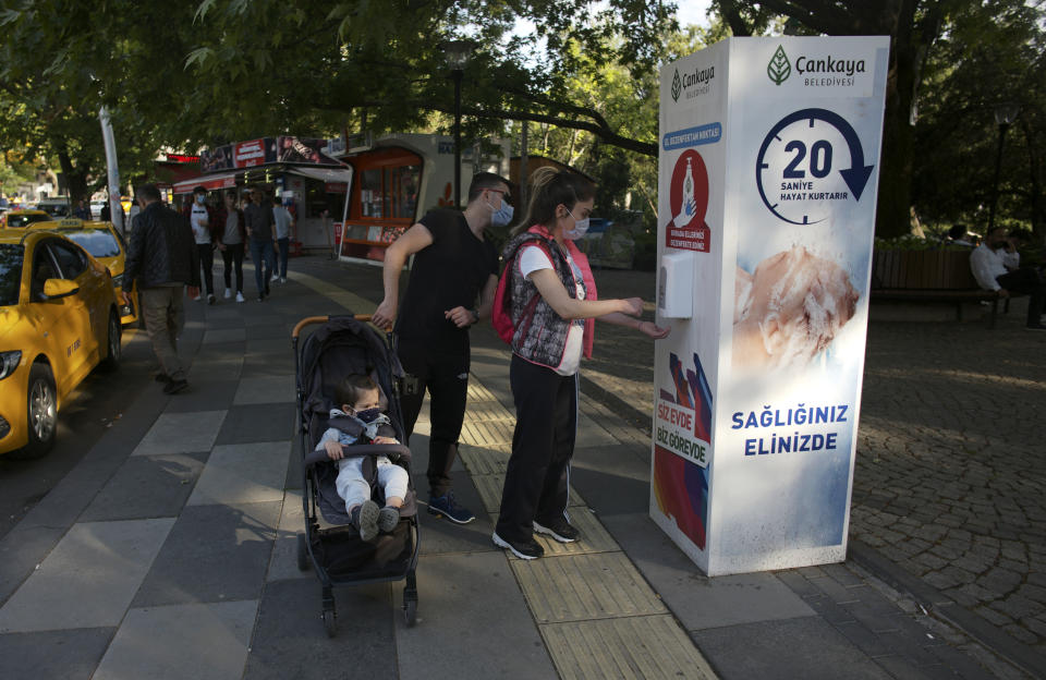 People wearing face masks to protect against the coronavirus, use disinfectant at the entrance of a public garden, in Ankara, Turkey, Sunday, June 14, 2020. Turkey's President Recep Tayyip Erdogan has revealed Tuesday new plans to ease restrictions in place to curb the spread of the coronavirus, including the July 1 reopening of theaters, cinemas and other entertainment centers. (AP Photo/Burhan Ozbilici)