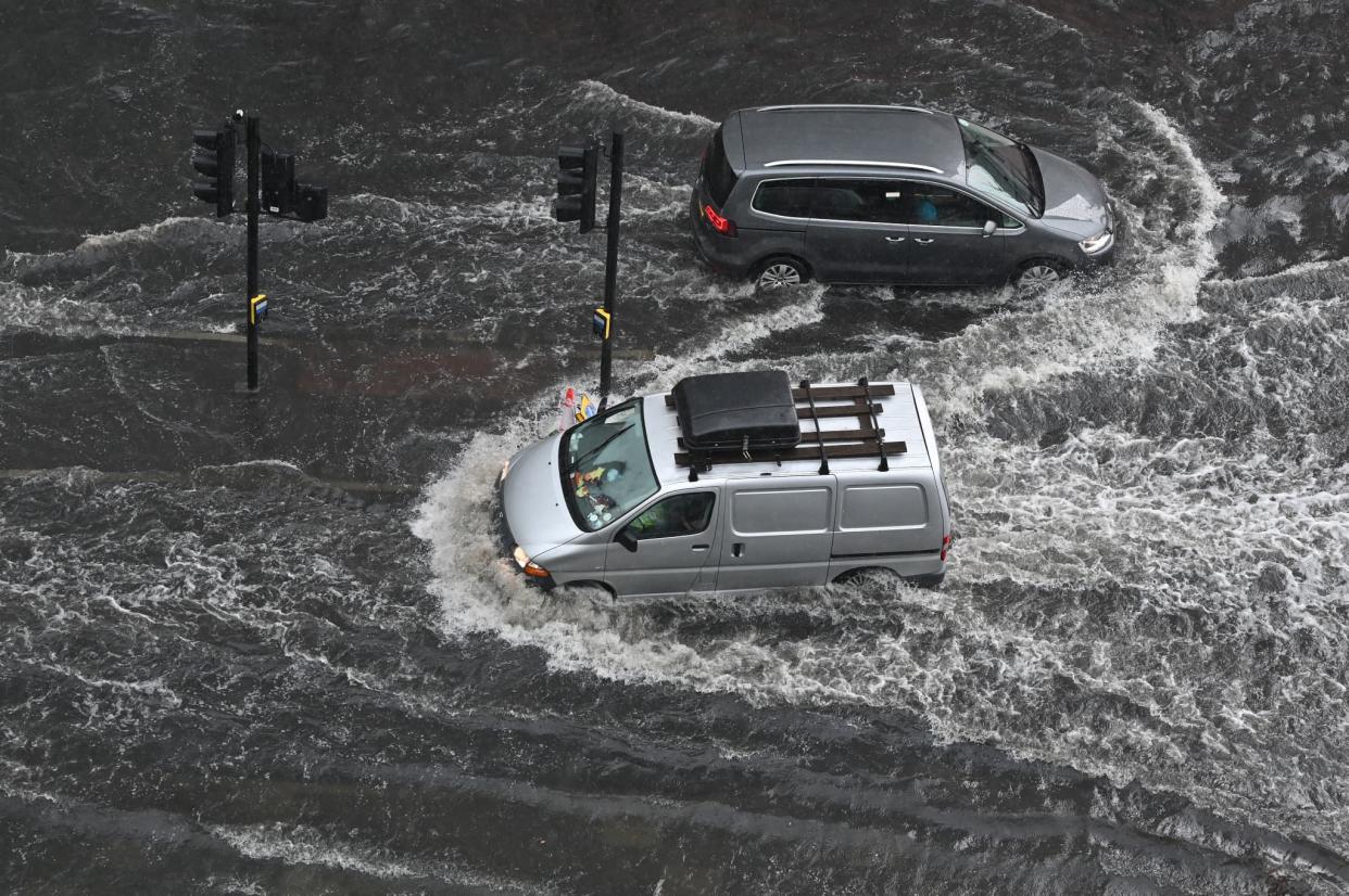 De voitures circulent tant bien que mal sur une chaussée inondée, dans le quartier Nine Elms de Londres, dimanche 25 juillet 2021 - Justin Tallis - AFP