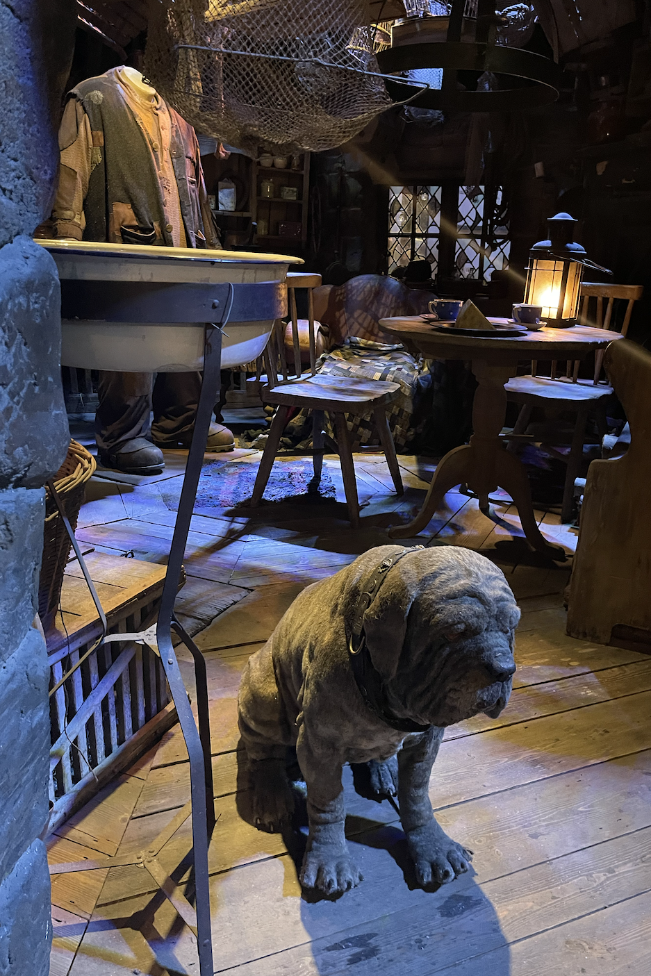 A large dog statue stands in a dimly lit, rustic room with wooden furniture and nautical decor