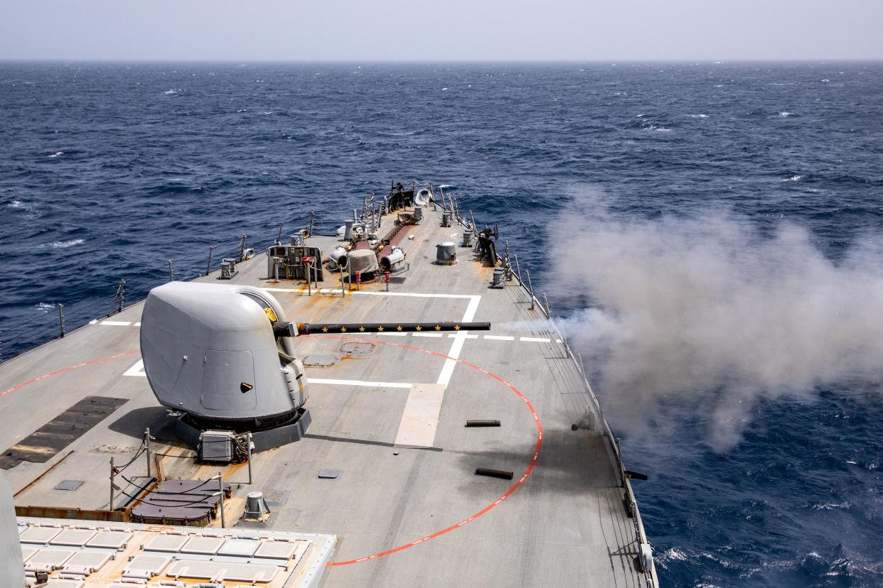 A gun system aboard a ship firing, producing smoke.