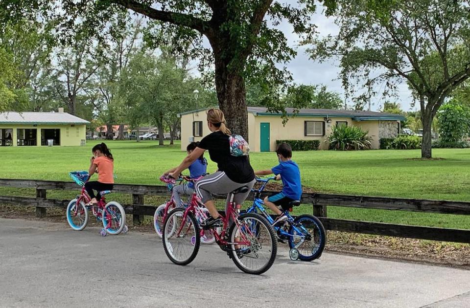 A woman and three children bike in Tropical Park. The three children wore masks but the woman with them did not. The park requires facial coverings for all visitors, with exceptions for children under 2, those with preexisting conditions that restrict breathing and those practicing strenuous physical activity.