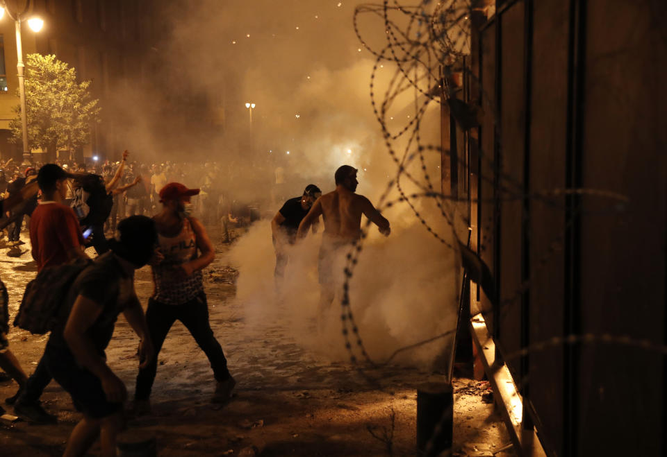 Protesters try to remove metal barrier that set by security forces, as they clash with the Lebanese riot police, during anti-government protest following Tuesday's massive explosion which devastated Beirut, Lebanon, Sunday, Aug. 9. 2020. (AP Photo/Hussein Malla)