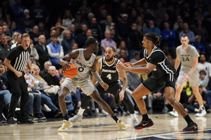 Xavier guard Souley Boum (0) is guarded by Providence's Jared Bynum (4) and Bryce Hopkins during overtime of an NCAA college basketball game, Wednesday, Feb. 1, 2023, in Cincinnati. (AP Photo/Jeff Dean)