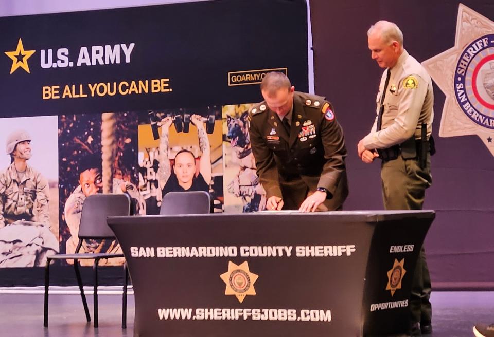 U.S. Army Lt. Col. Matthew Upperman, left, and San Bernardino County Sheriff Shannon Dicus, right, sign a memorandum of understanding bringing the sheriff's department into an Army program meant to fast-track soldiers into law enforcement careers after military service.