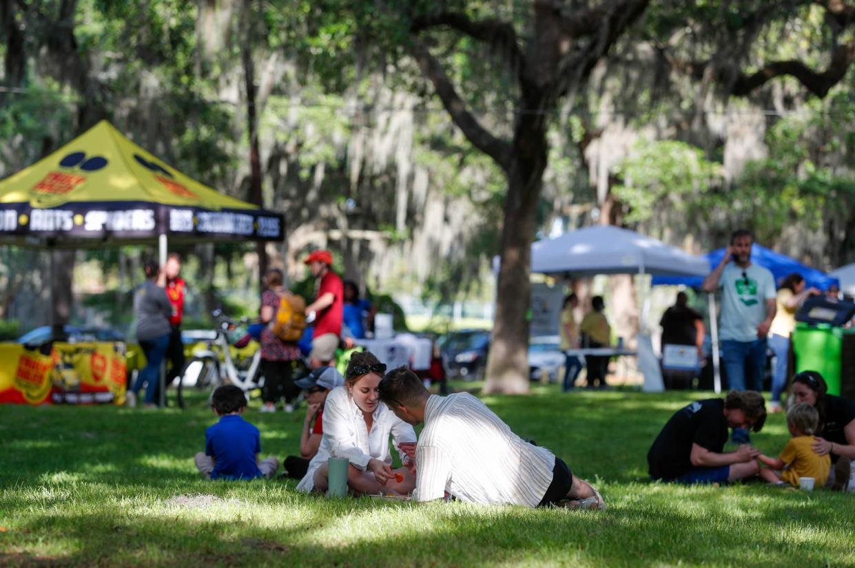 Families relax on the grass during Earth Day Savannah in Daffin Park.