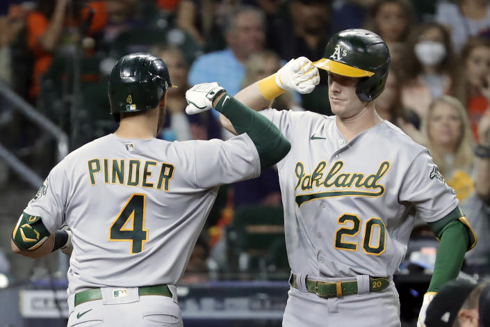 Oakland Athletics' Chad Pinder (4) and Mark Canha (20) bump forearms as they celebrate a home run by Pinder during the fourth inning of a baseball game against the Houston Astros, Friday, Oct. 1, 2021, in Houston. (AP Photo/Michael Wyke)