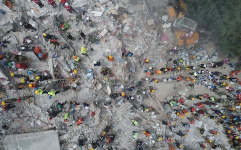 This aerial view shows rescuers, firefighters, policemen, soldiers and volunteers searching for survivors in a flattened building in Mexico City  - Credit: MARIO VAZQUEZ/AFP/Getty Images