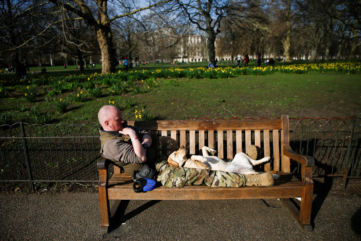 A man lies on a bench with his dog in St James Park in central London. Source: Reuters