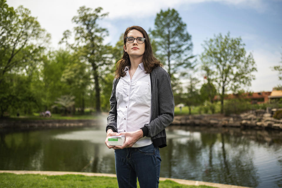 Erin Stille, a transgender woman, poses for a portrait, in St. Peters, Mo., Friday, April 28, 2023. Stille holds a package of androgen-blocking pills that she ordered from a Taiwan-based supplier. (AP Photo/Michael Thomas)