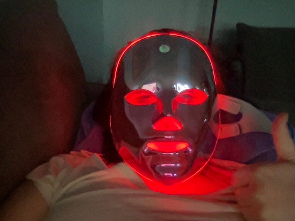 A person Lying on the couch and using an LED mask.