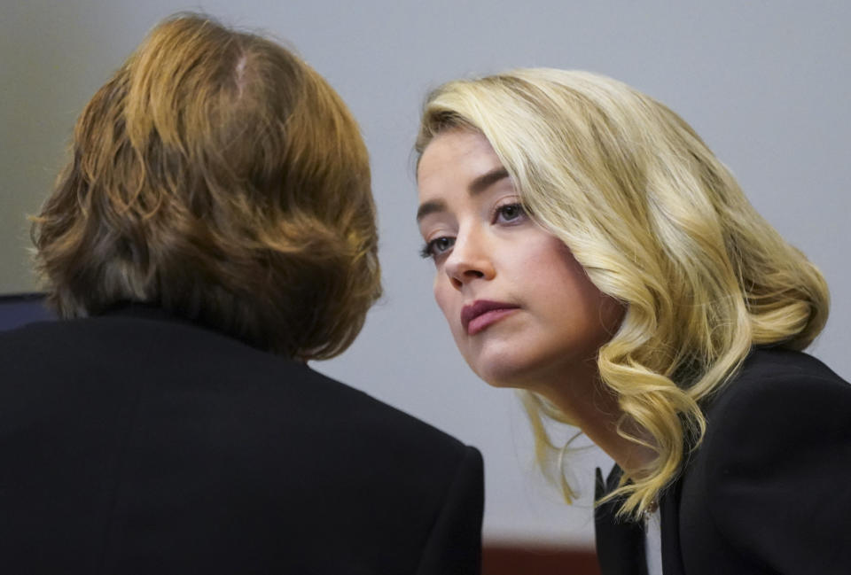 Actor Amber Heard talks with her lawyer Elaine Bredehoft in the courtroom at the Fairfax County Circuit Courthouse in Fairfax, Va., Wednesday, May 18, 2022. Actor Johnny Depp sued his ex-wife Amber Heard for libel in Fairfax County Circuit Court after she wrote an op-ed piece in The Washington Post in 2018 referring to herself as a "public figure representing domestic abuse." (Kevin Lamarque/Pool Photo via AP)