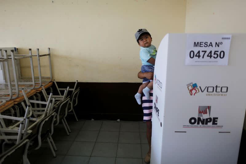 Foto del domingo de una mujer votando con su hijo en Lima