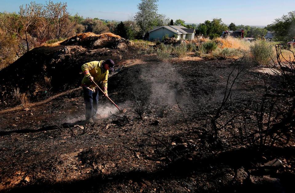A Kennewick firefigher uses a shovel to extinguish a smoldering hot spot early Monday morning on the eastern edge of Zintel Canyon near South 8th Place.