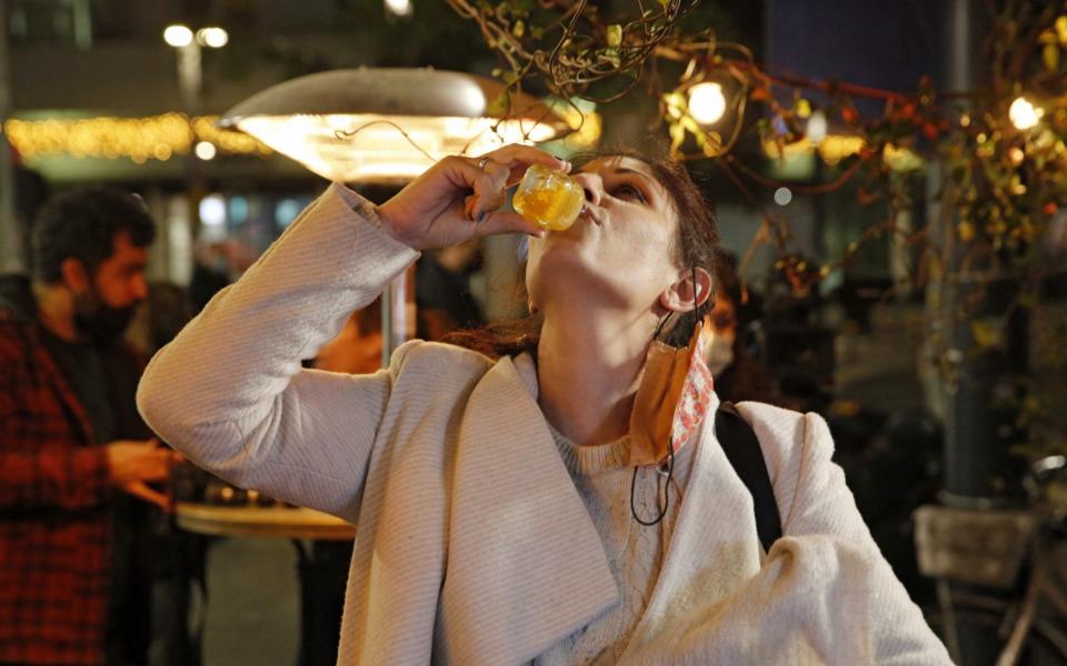 An Israeli woman takes a shot after receiving her Covid-19 vaccine at a bar in the coastal city of Tel Aviv  - Gil Cohen-Magen/AFP