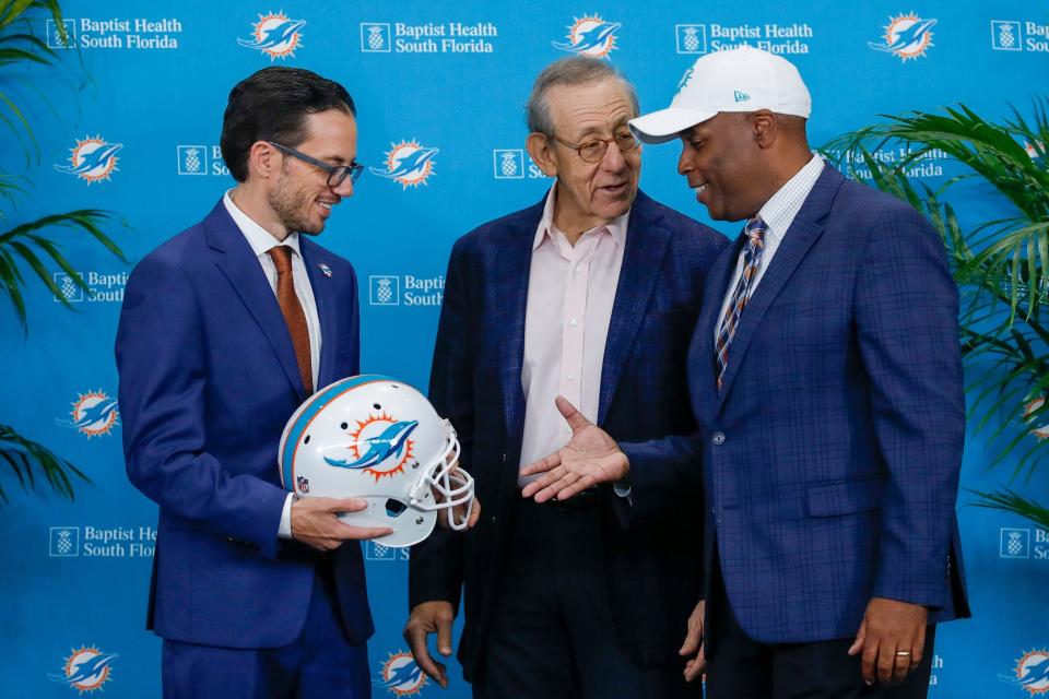 New Dolphins coach Mike McDaniel, left, shakes hands with General Manager Chris Grier as owner Stephen Ross looks on Thursday in Miami Gardens. The Dolphins were docked a first-round pick in 2023 and a third-rounder in 2024 and owner Stephen Ross was suspended through mid-October and fined $1.5 million for damage to the integrity of the game, NFL Commissioner Roger Goodell announced Tuesday. The penalties largely surround the DolphinsÕ flirtation with quarterback Tom Brady Ñ not only before the 2021 season when Brady was a member of the Tampa Bay Buccaneers but extending all the way back to the 2019-20 season when he was with the New England Patriots.