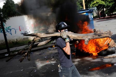 An opposition supporter carries a piece of wood to build a barricade on the street during a strike called to protest against Venezuelan President Nicolas Maduro's government in Caracas. REUTERS/Carlos Garcia Rawlins