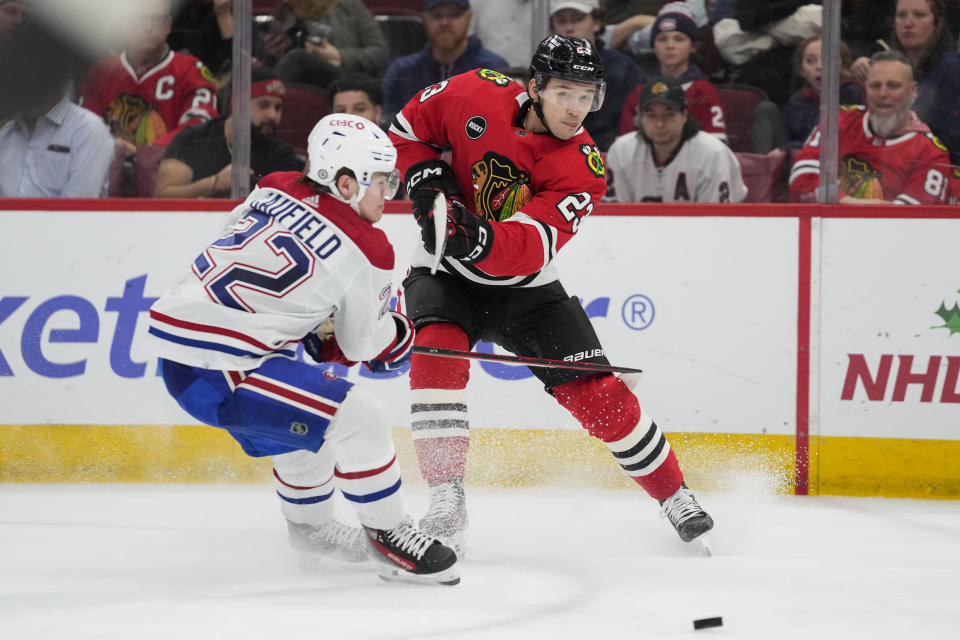 Chicago Blackhawks center Philipp Kurashev, right, sends the puck past Montreal Canadiens right wing Cole Caufield during the second period of an NHL hockey game Friday, Dec. 22, 2023, in Chicago. (AP Photo/Erin Hooley)