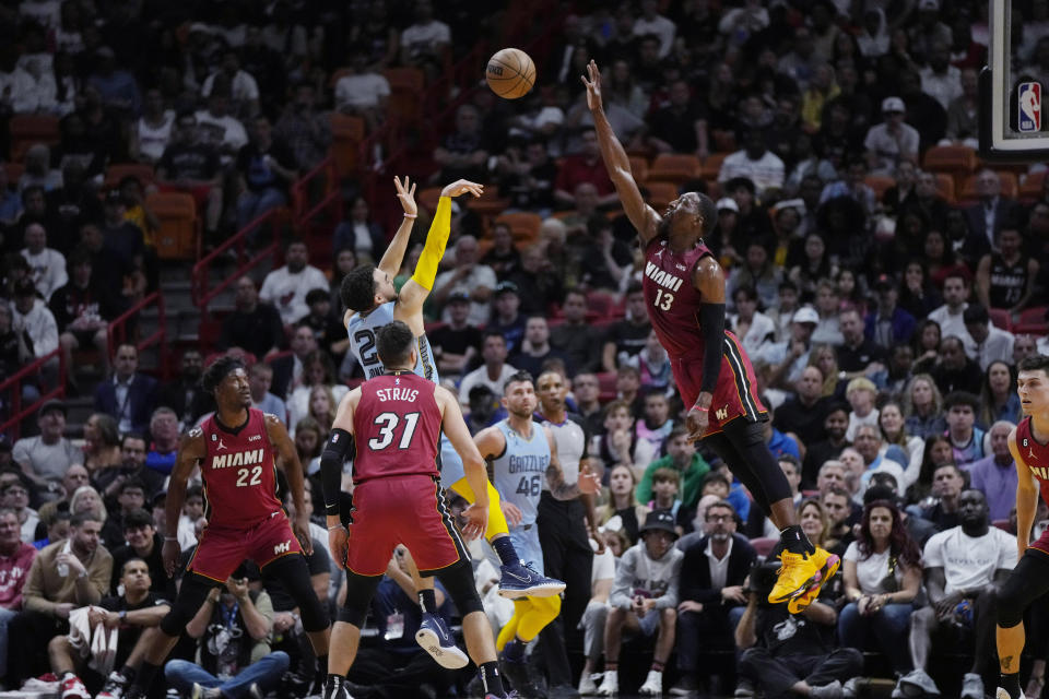 Miami Heat center Bam Adebayo (13) jumps while defending against a shot by Memphis Grizzlies guard Tyus Jones (21) during the first half of an NBA basketball game Wednesday, March 15, 2023, in Miami. (AP Photo/Rebecca Blackwell)