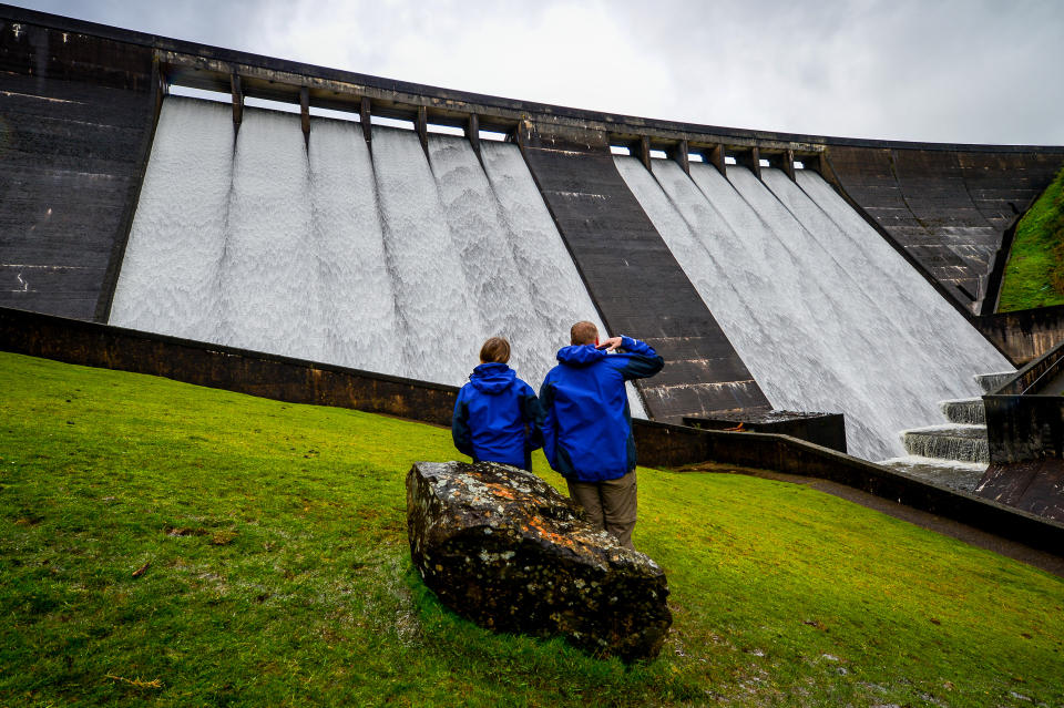 <p>People look at the overflowing spillway at Meldon Dam in Dartmoor, Devon, after heavy rain in the South West, which could see new rainfall records set for May in Devon and Wales. Picture date: Monday May 24, 2021.</p>
