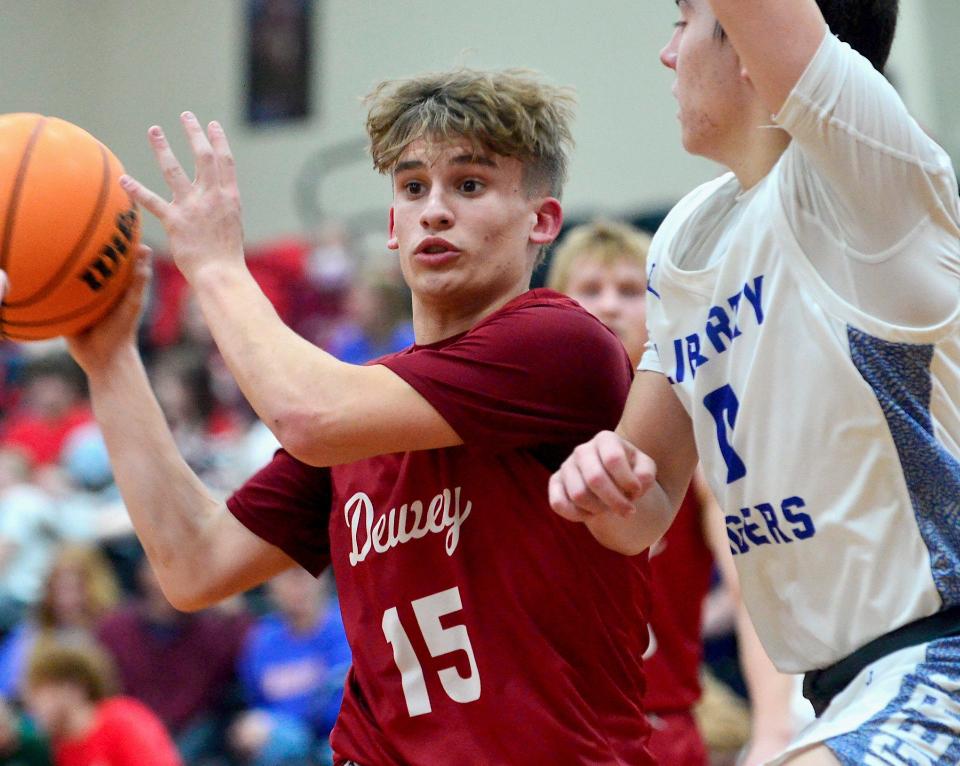 Dewey High's Easton Davis, left, scans his options during a boys basketball battle against Liberty High on Jan. 20, 2023, in the Caney Valley Invitational.