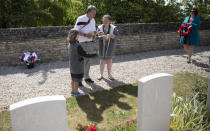 British expatriate Steven Oldrid, center, directs children where to lay wooden crosses with names of WWII dead during D-Day ceremonies at the local war cemetery in Benouville, Normandy, France on Saturday, June 6, 2020. Due to coronavirus measures many relatives and veterans will not make this years 76th anniversary of D-Day. Oldrid will be bringing it to them virtually as he places wreaths and crosses for families and posts the moments on his facebook page. (AP Photo/Virginia Mayo)