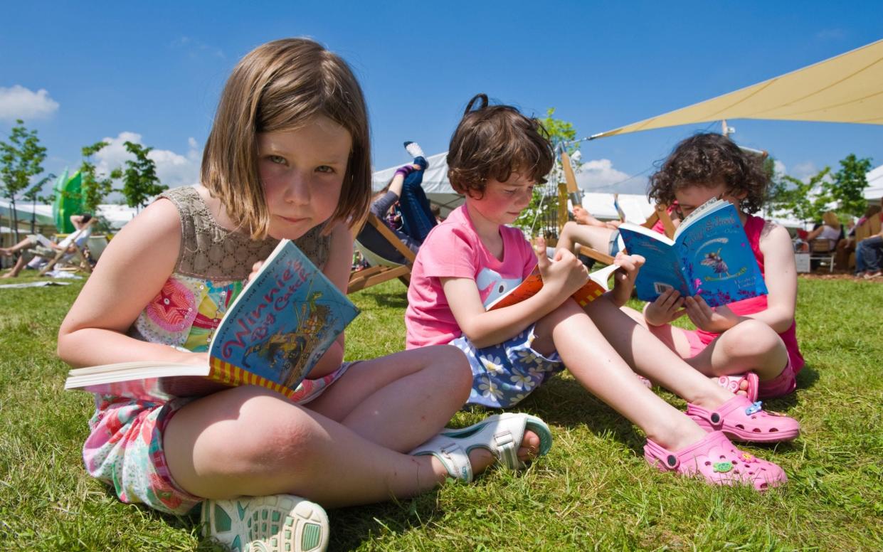 Three young girls sitting on the grass reading books in the summer sunshine at Hay Festival 2010 Hay on Wye Powys Wales UK - https://www.alamy.com 