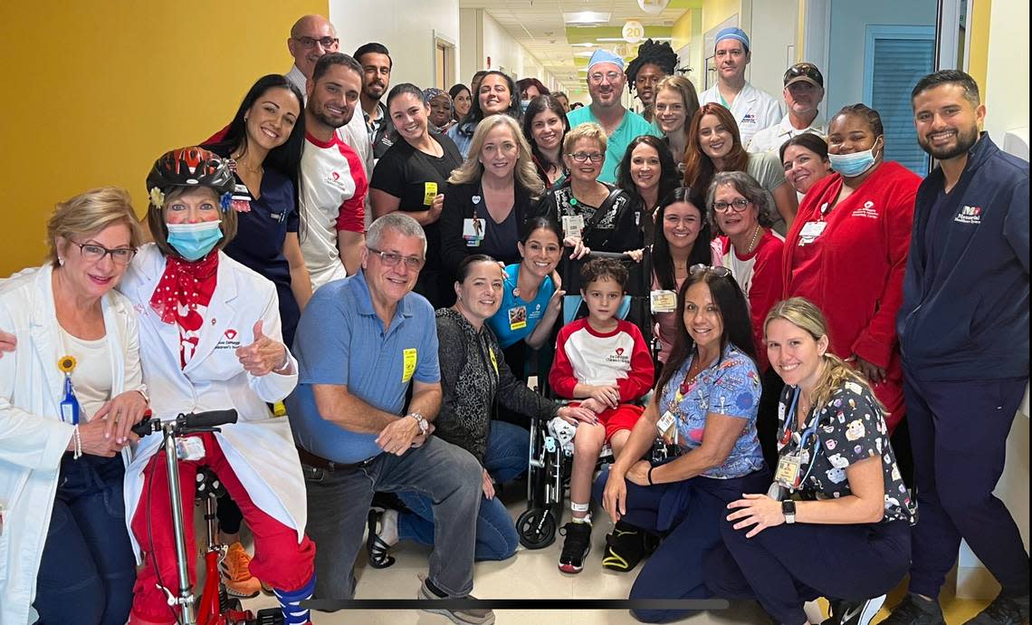 Jacob,7, and his dad Anthony Estrada, in a white shirt with red sleeves rolled up on the left, pose with the team at Joe DiMaggio Children’s Hospital who helped Jacob survive and recover from his injuries.
