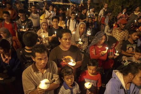 Indonesians hold up candles during a candle light vigil for the victims of AirAsia flight QZ8501 at Surabaya December 31, 2014. REUTERS/Athit Perawongmetha