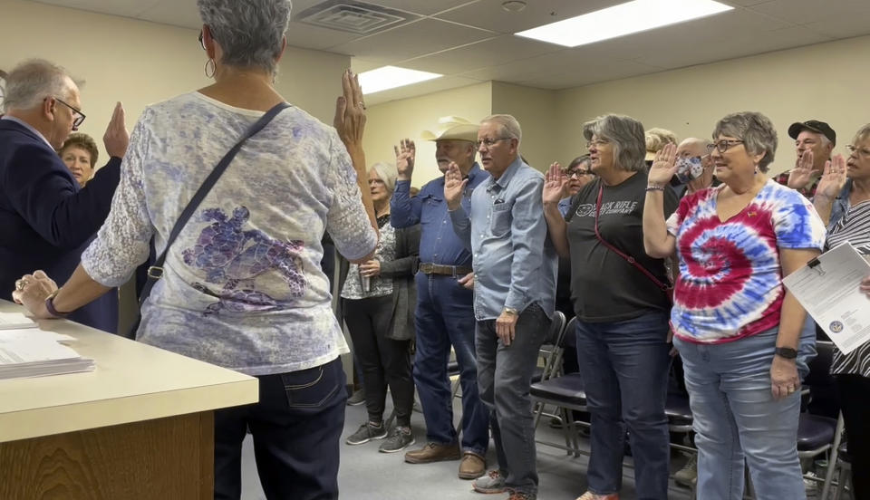 FILE - In this image from video, Nye County Clerk Mark Kampf, far left, in suit, swears in a group of residents who will hand count early ballots cast in the rural county about halfway between Las Vegas and Reno, Oct. 26, 2022, in Pahrump, Nev. An AP survey shows the majority of candidates running this year for the state posts that oversee elections oppose the idea of hand counting ballots, a laborious and error-prone process that has gained favor among Republicans who have been inundated with unfounded voting machine conspiracy theories. (AP Photo/Gabe Stern, File)