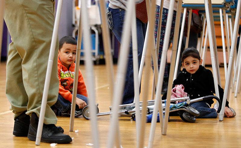 Francis Rosko (L), age 6, and his sister Ellen Rosko (R), age 5, wait under a voting booth while their mother casts in Cleveland. Photo: AAP