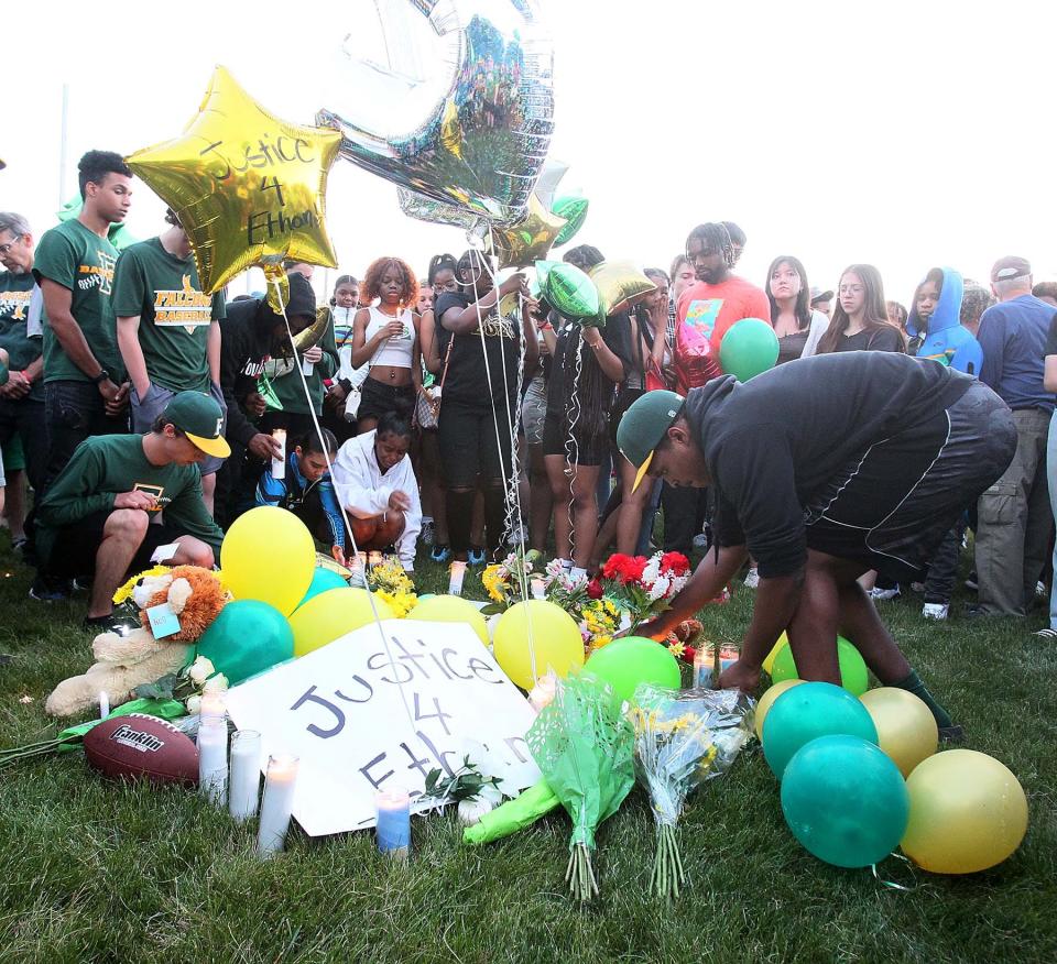 Family and friends gather around a memorial for Ethan Liming at the Firestone High School baseball field Friday evening.