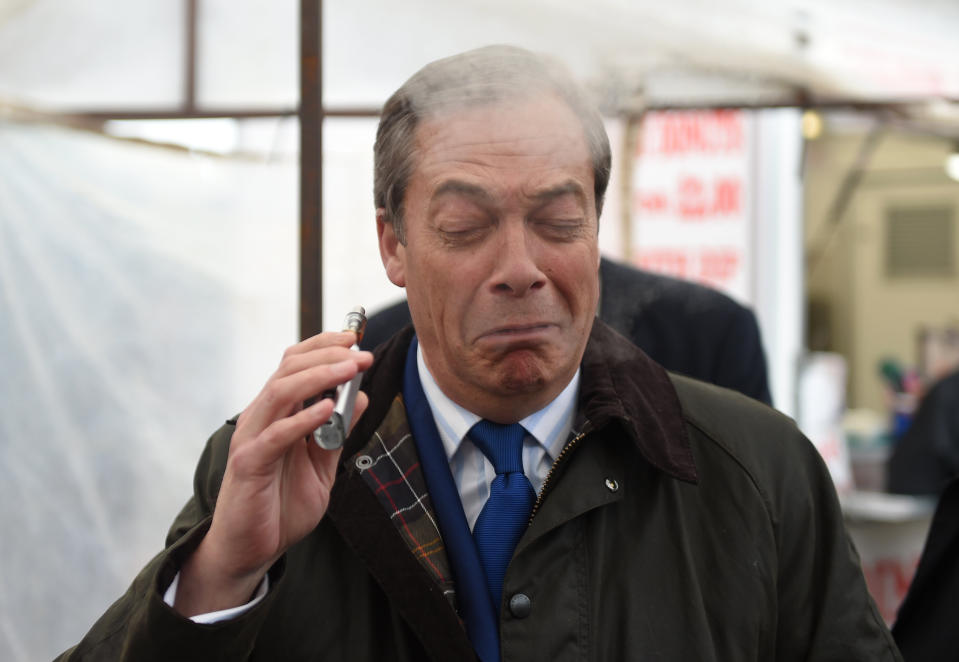 Brexit Party leader Nigel Farage coughs as he samples an e-cigarette during a  walkabout in Lincoln on Friday (PA)