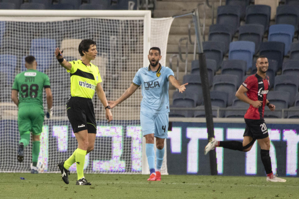 Referee Sapir Berman, foreground, works during an Israeli Premier League soccer match between Hapoel Haifa and Beitar Jerusalem in the northern Israeli city of Haifa, Monday, May 3, 2021. Israeli soccer's first transgender soccer referee took the field Monday for the first time since coming out publicly as a woman last week. (AP Photo/Sebastian Scheiner)