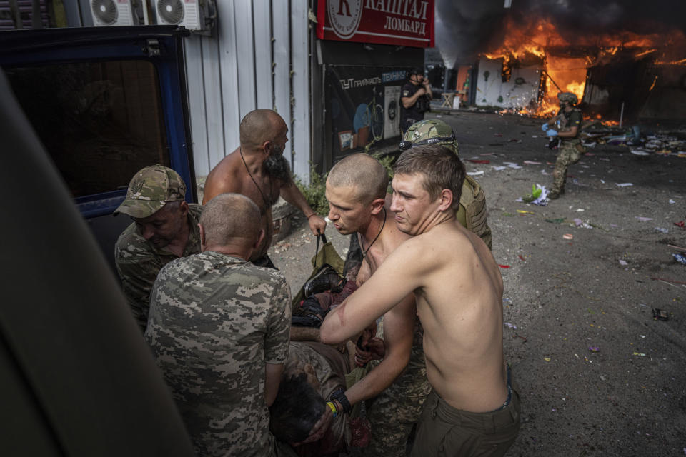 Ukrainian soldiers move to the ambulance an injured woman after a Russian rocket attack on a food market in the city center of Kostiantynivka, Ukraine, Wednesday, Sept. 6, 2023. (AP Photo/Evgeniy Maloletka)