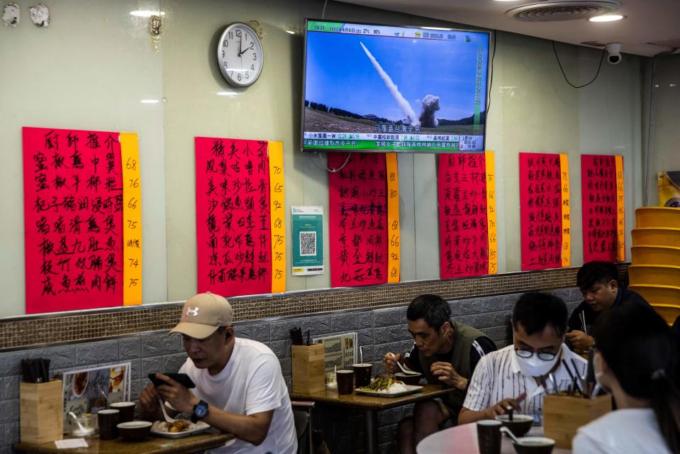 A television (top) in a restaurant in Hong Kong on 5 August 2022, shows a missile being launched during military exercises being held by China around the island of Taiwan (AFP via Getty Images)