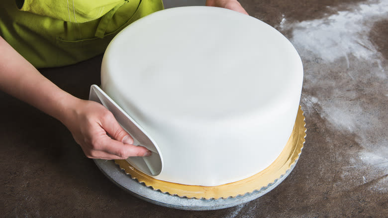 Person applying fondant to cake