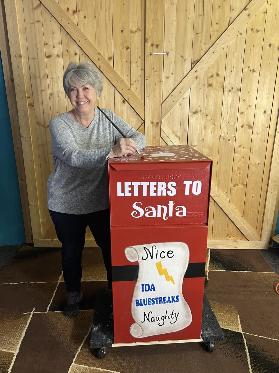 Karen Lewis is shown with Ida's new Santa mailbox. Lewis spent a couple weeks designing and painting the mailbox.